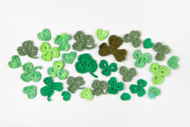 St Patrick's Day concept. Composition made of knitted green shamrocks on a gray background. Holiday sign and knitted clover leaf. Copy space, flat lay, place for text