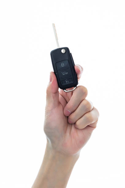 Human hand holding car remote key on white background