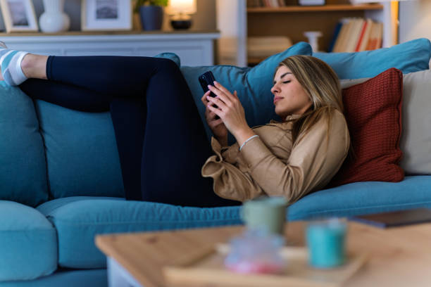 istock A young woman uses a mobile phone reading the latest news while preparing for breakfast 2204394219