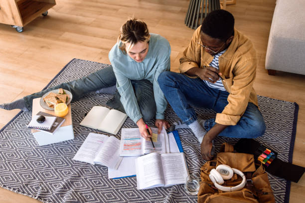 istock Students doing their school tasks at home together on floor surrounded by books. 2204394651