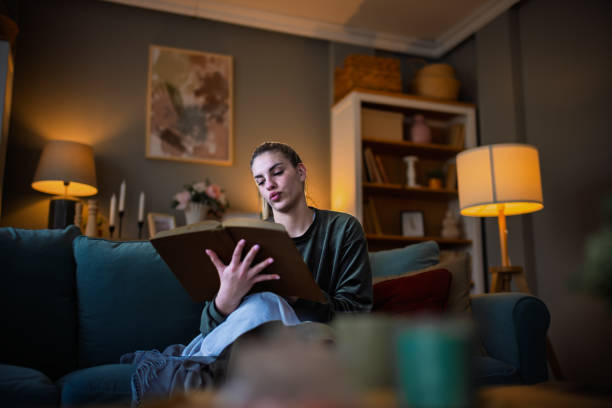 istock Woman sitting on comfy couch reading a book and drinking 2204395048