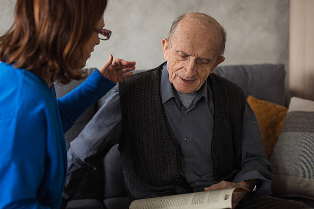istock Cheerful elderly man having volunteer reading to him 2204395172