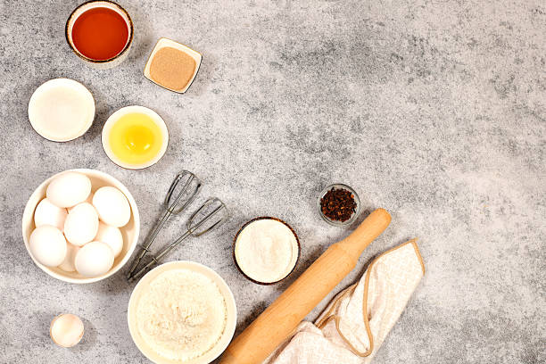 istock Kitchen background of food preparation with space for text. Culinary ingredients for making pie and bread, recipe with eggs, flour, sugar, honey, cinnamon, yeast and butter. Modern bakery concept, 2204395227