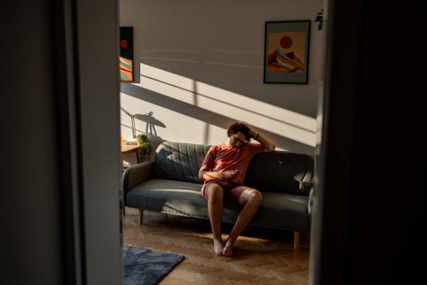 istock Student sitting on a sofa at home with sun light on the wall 2204396989