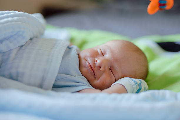 istock Smiling newborn baby dreaming on the bed 2204397753