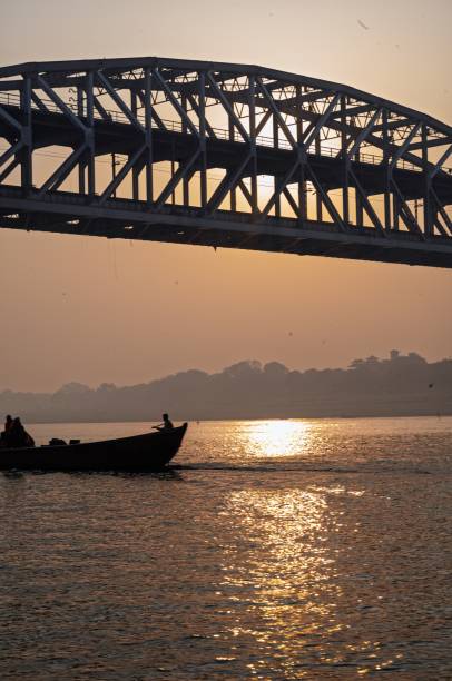 istock Silhouette of a boat under a bridge during sunset on a calm river 2204398190
