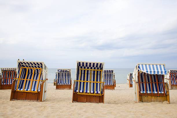 istock On Kolobrzeg's sandy beach, vintage wicker baskets with white-blue stripe fabric offer a cool shade and coastal charm. 2204399678