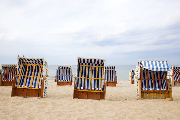 istock Traditional wood and wicker beach baskets, lined in white-blue stripes, dot Kolobrzeg's shore with the Baltic Sea in view. 2204399681