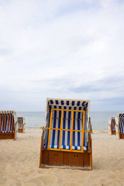 istock Rustic beach baskets with white-blue stripes add character to Kolobrzeg's sandy beach, with the Baltic Sea and soft clouds beyond. 2204399828