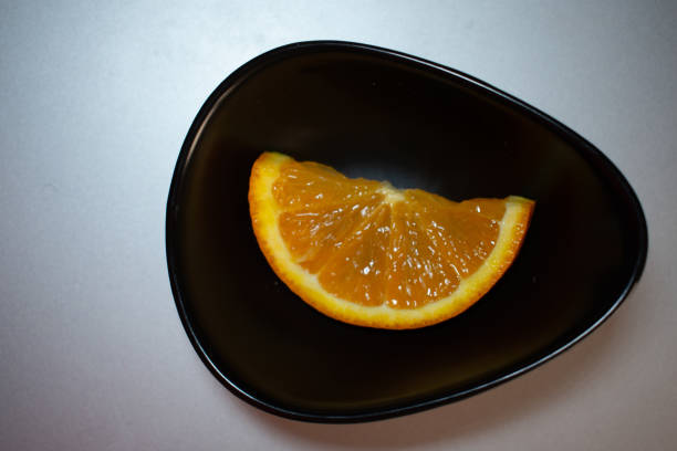 istock a piece of orange in a black plate 2204399934
