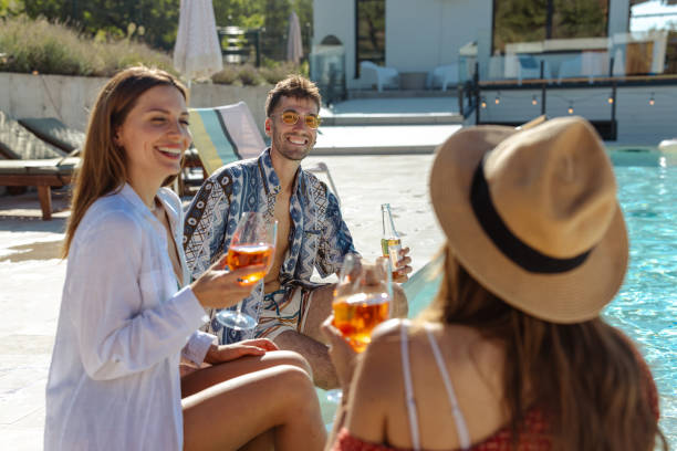istock Group of friends enjoying drinks by a pool on a sunny day 2204409466