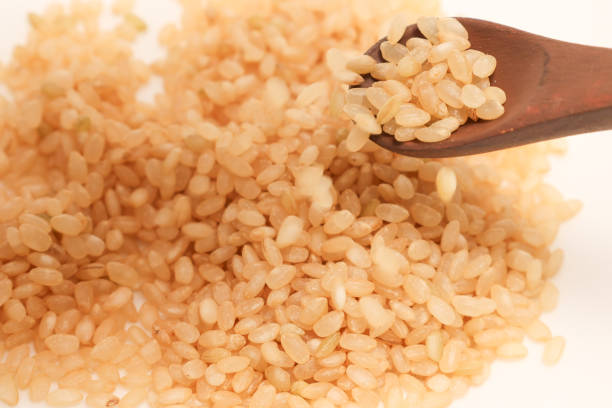 Brown rice isolated on a white background with a wooden spoon.