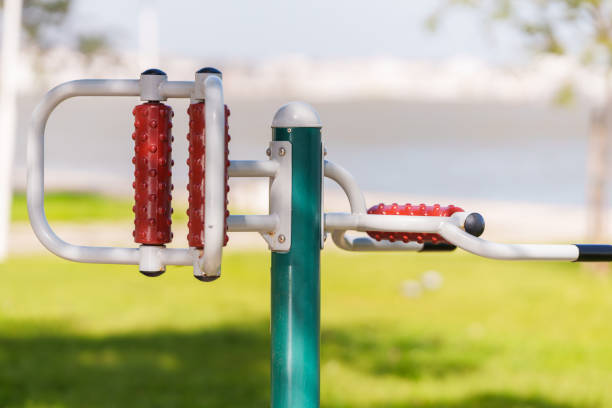 Outdoor fitness equipment with rotating hand wheels is installed in a park for arm and shoulder exercises.