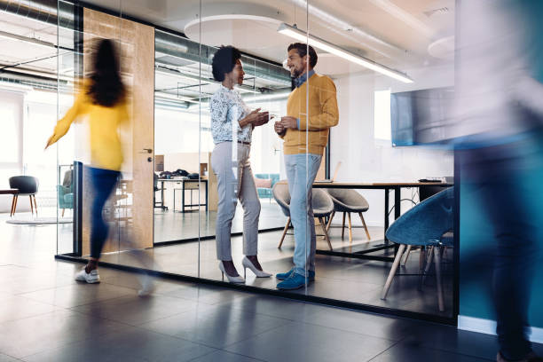 istock Business persons talking inside a glass room in a modern open office space 2204418509