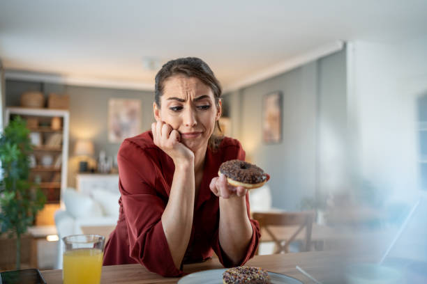 Woman feeling guilty while eating chocolate donut at home