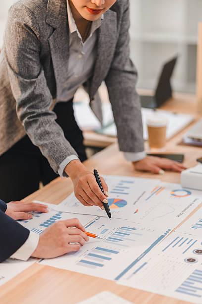 Business professionals analyzing financial charts and graphs during meeting, discussing data trends and strategies in modern office environment