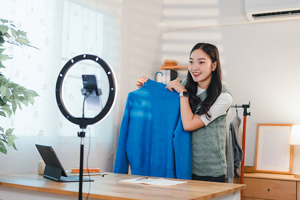 istock woman live streaming while showcasing blue sweater in cozy home setting 2204447251