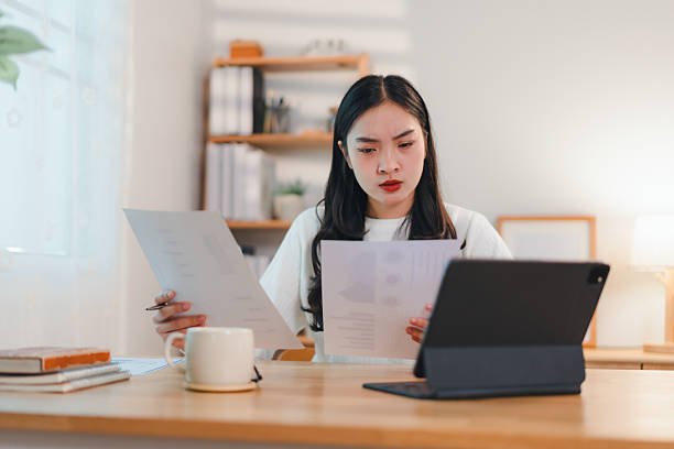 istock focused woman working at desk with documents and tablet in bright home office 2204447451