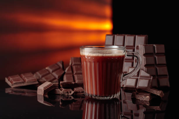 istock Hot chocolate and broken bitter chocolate bar on a black reflective background. 2204447982