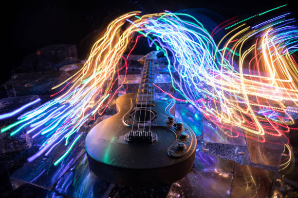 Music Concept: Guitar Miniature on a Dark Background with Vivid Light, Smoke, and Fire Effects. Golden electro guitar under a Dramatic Spotlight. Ice Glass blocks decor
