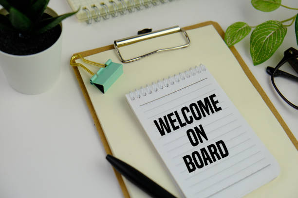 istock Text Welcome On Board on a business card lying next to notepad with cup coffee and calculator. Business concept 2204450583
