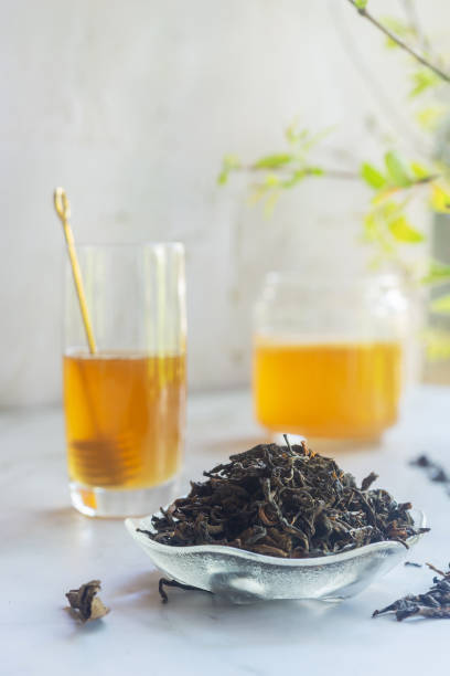 istock loose leave green tea in a glass bowl on white table. 2204459857