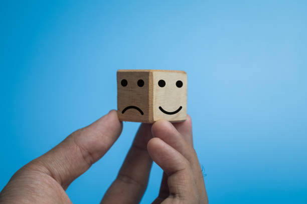 smile expression emoji on bright side and bad expression on dark side on wooden cube on isolated o black dark background