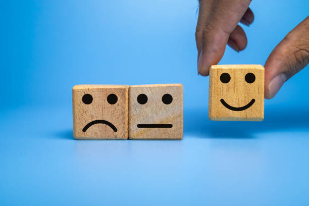 istock sad, flat and happy face expression emoticon on wooden cubes isolated on black dark background 2204461425