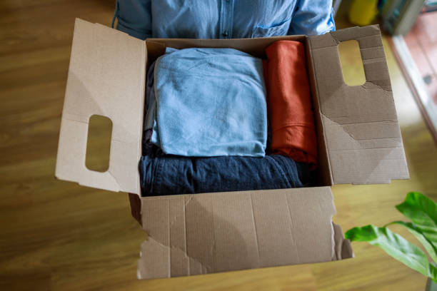 istock Neatly Packed Clothes for Donation in a Cardboard Box 2204463443