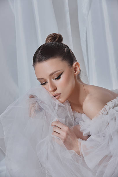 istock model in a flowing, sheer outfit elegantly interacts with soft fabric in a serene indoor environment. scene captures contemporary fashion and artistry at its best 2204470662