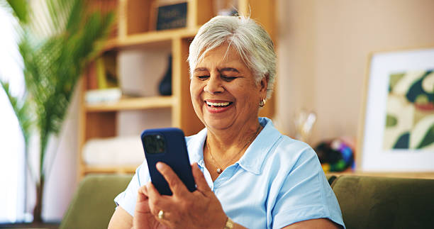 istock Senior woman, laugh and texting on sofa in home with chat, contact or scroll with connection on web. Elderly person, smartphone and happy on couch, funny memory or mobile app on social media in house 2204473052