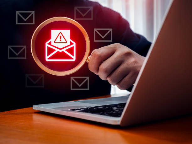 istock Phishing emails scam alert, fraud sms message concept. Warning alert icon in opened envelope icon, fraudulent email, in magnifying glass lens, found while man working online with laptop computer. 2204473767