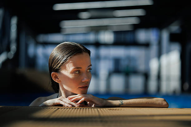 Woman with wet hair looking away at poolside in spa complex