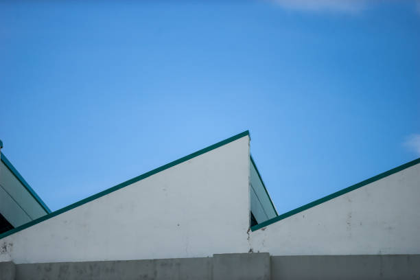 The image showcases a modern architectural design with geometric rooflines contrasting against a clear blue sky, highlighting clean lines and minimalistic appeal.