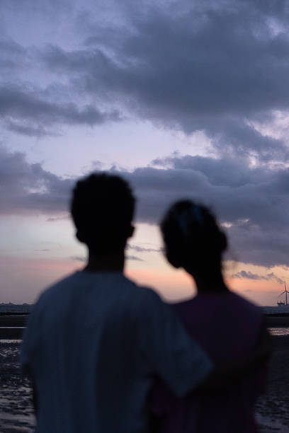 A young couple watching the sunrise by the seaside, a romantic scene
