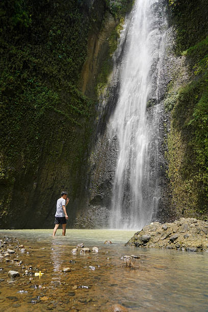 istock young asian indonesian man standing against the waterfall 2204476350