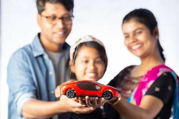 An Indian middle class happy family with a toy car on white background, buying car concept