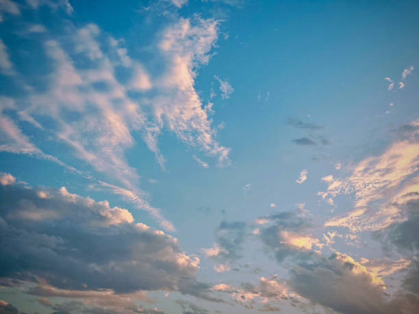 Blue sky filled with fluffy white clouds. Soft light illuminates the clouds, creating a serene and peaceful atmosphere in the expansive scene.