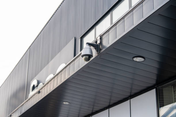 istock Security camera mounted on modern building facade capturing urban life moments during a cloudy day 2204479389