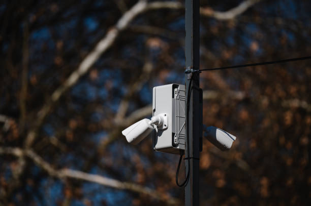 istock Surveillance cameras mounted on a pole with blurred trees in the background 2204480641