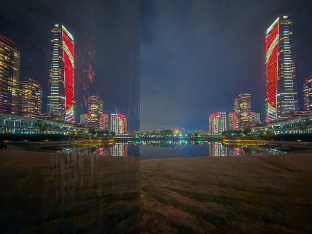 ShenZhen, China - February 12, 2025 : Night view of a modern building complex illuminated at night. Cityscape reflects in water, showcasing urban architecture under a dark sky.