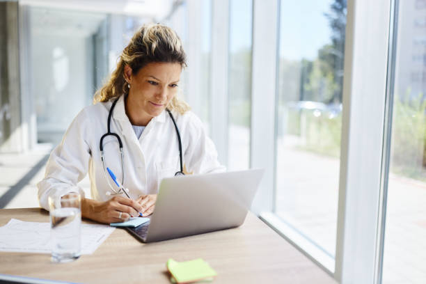 istock Female doctor taking notes while working on laptop in the office. 2204481263