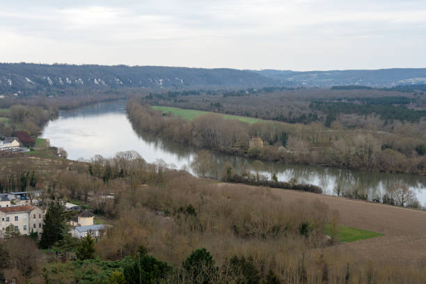 istock Beautiful view of the Seine River winding through La Roche-Guyon while trees stand bare in early spring under a cloudy sky 2204488806