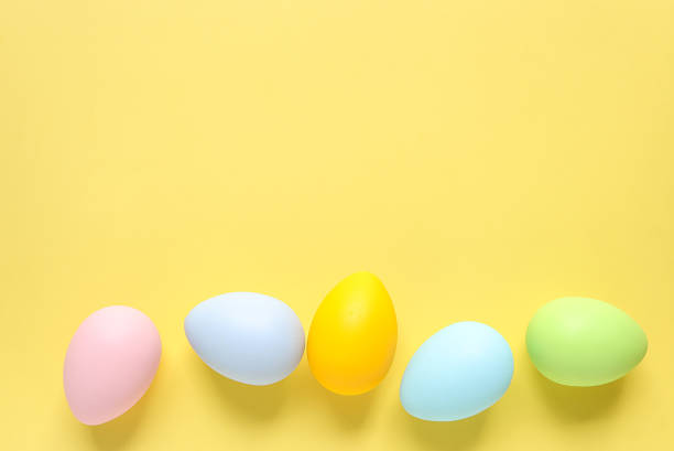 istock Easter eggs painted in pastel colors on a yellow background. Easter celebration concept. Colorful easter eggs with place for text. 2204489839