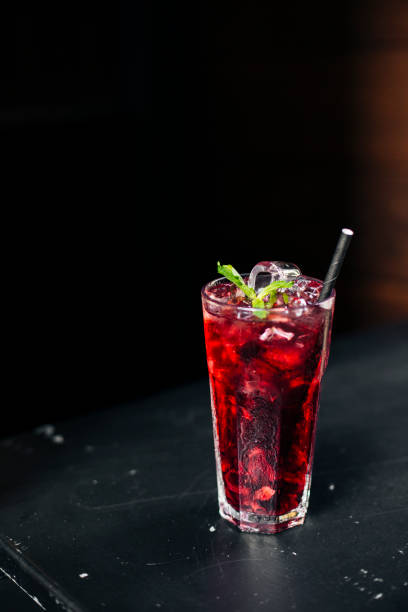 istock Refreshing iced hibiscus tea with ice cubes and basil garnish in a tall glass, vibrant red herbal drink with a straw, served against a dark background, healthy and organic beverage concept 2204490749