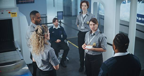 istock Female Security Officer Holding Boarding Pass, Explaining Procedures to Team of Workers 2204490823