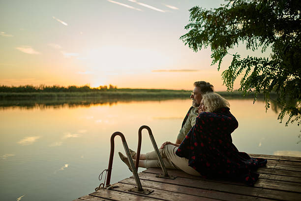 istock Senior couple enjoying sunset while relaxing on lake pier 2204491595