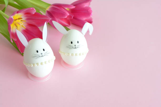 istock Easter bunny eggs with tulips on pink background copy space 2204493846
