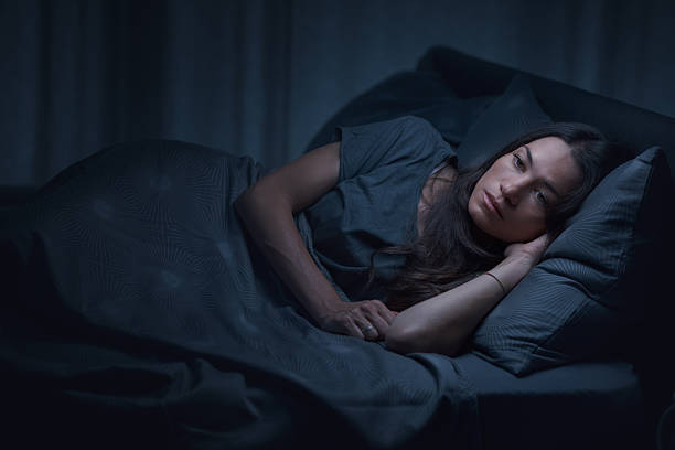 istock Sad young woman awake in bed at night 2204494943