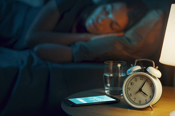 istock Woman sleeping and alarm ringing on her smartphone 2204495154